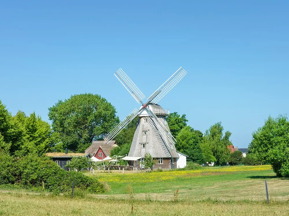 Windmühle zwischen Wiesen und Bäumen