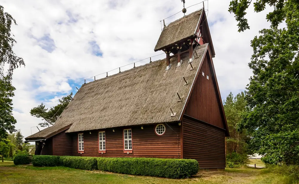 Fischerkirche Born aus Holz mit Rohrdach und Dachreiter unter Wolken