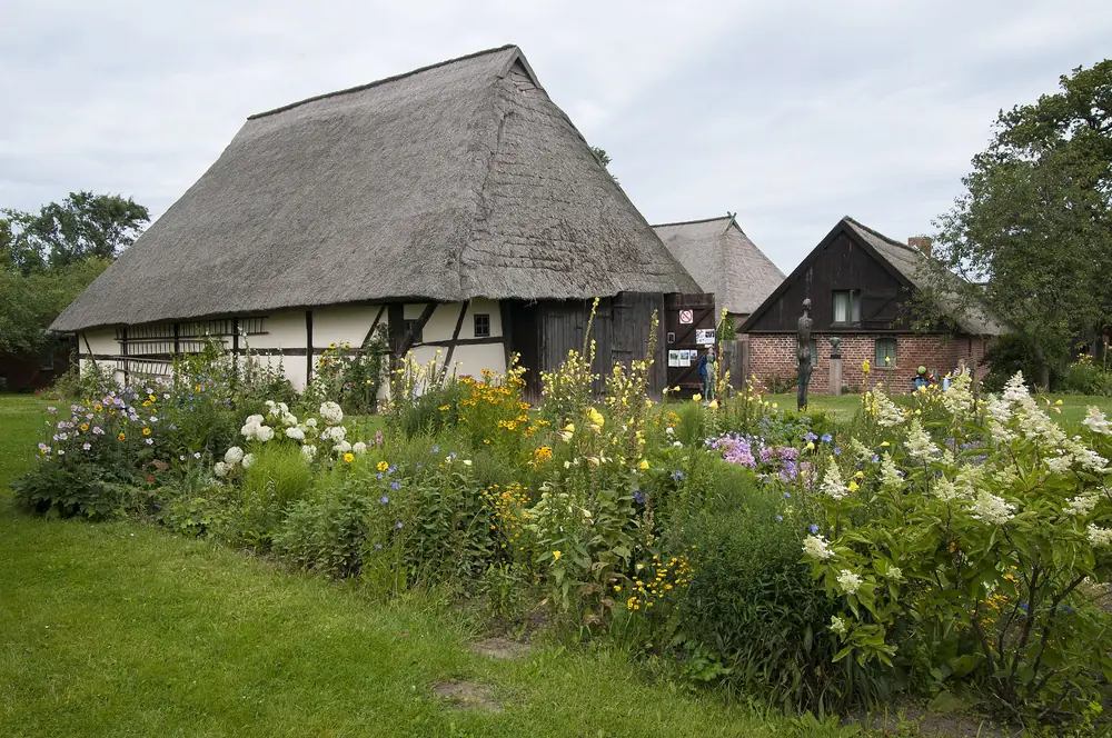Platzhalter, nicht sein Haus: Blühender Garten vor einem Rohrdachhaus