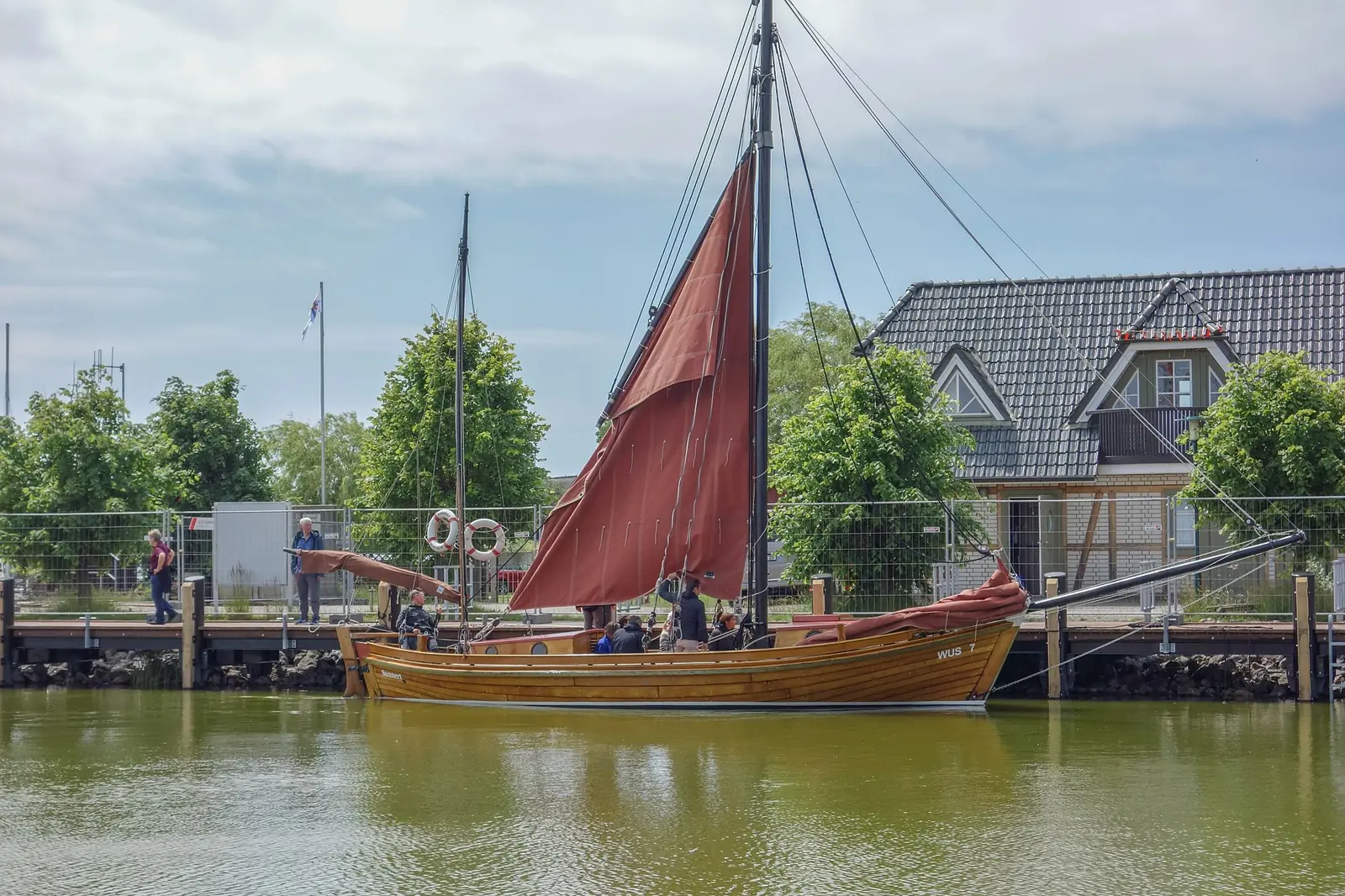 Zeesboot mit rotbraunem Segel am Steg im Boddenhafen