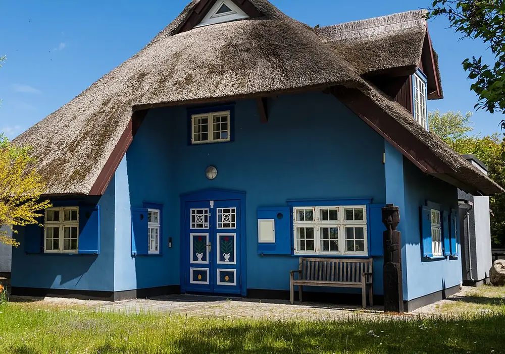 Blaue Fassade mit weißen Fenstern und Holztür