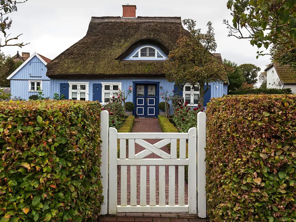 Rohrdachhaus mit weißer Gartenpforte in Born