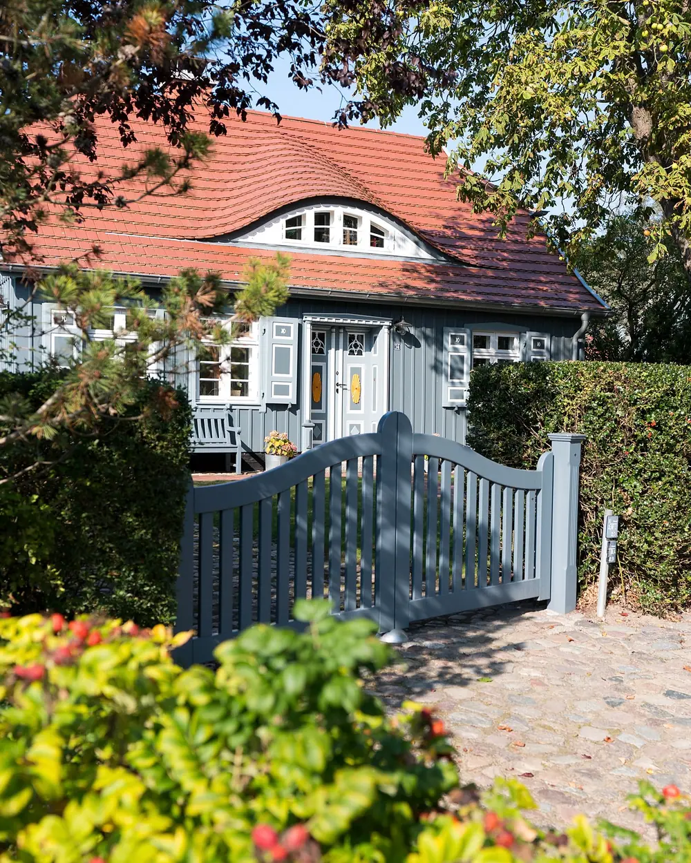 Gartentor und Haus mit rotem Dach in Wieck