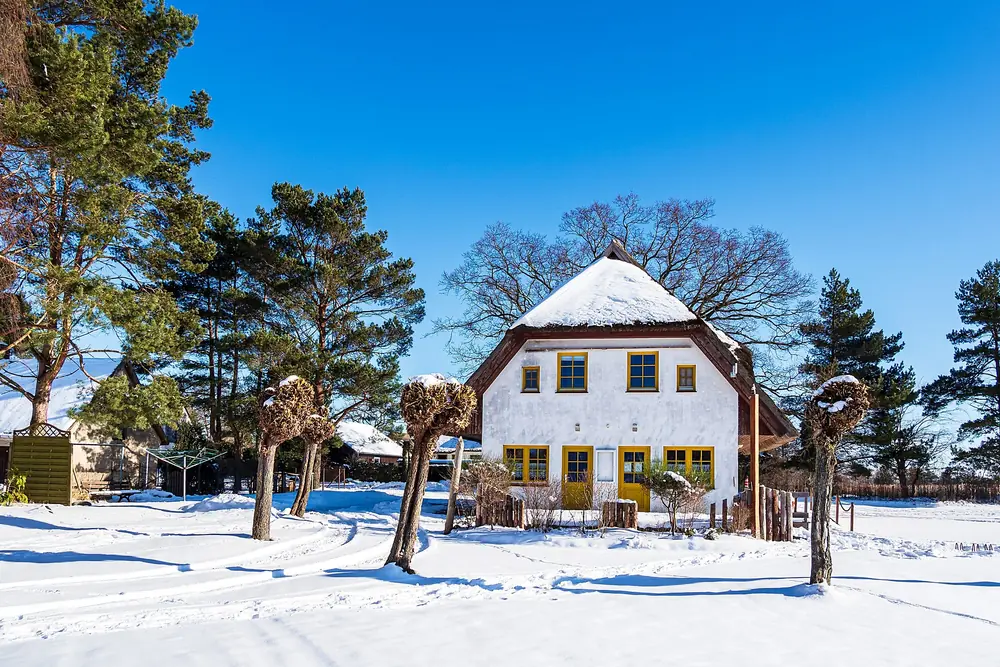 Platzhalter, nicht sein Haus: Rohrdachhaus im Schnee unter blauem Himmel