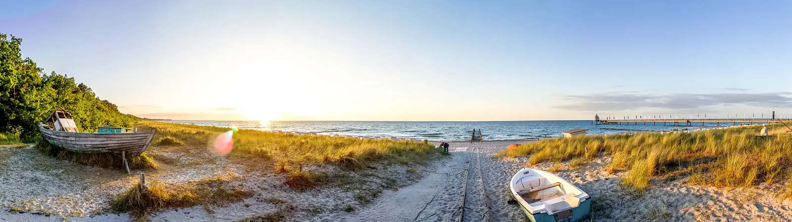 Weiter Strand von Zingst mit Dünen und Holzbooten im Morgenlicht
