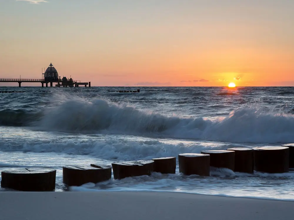 Wellen an der Buhne vor der Seebrücke bei Sonnenuntergang